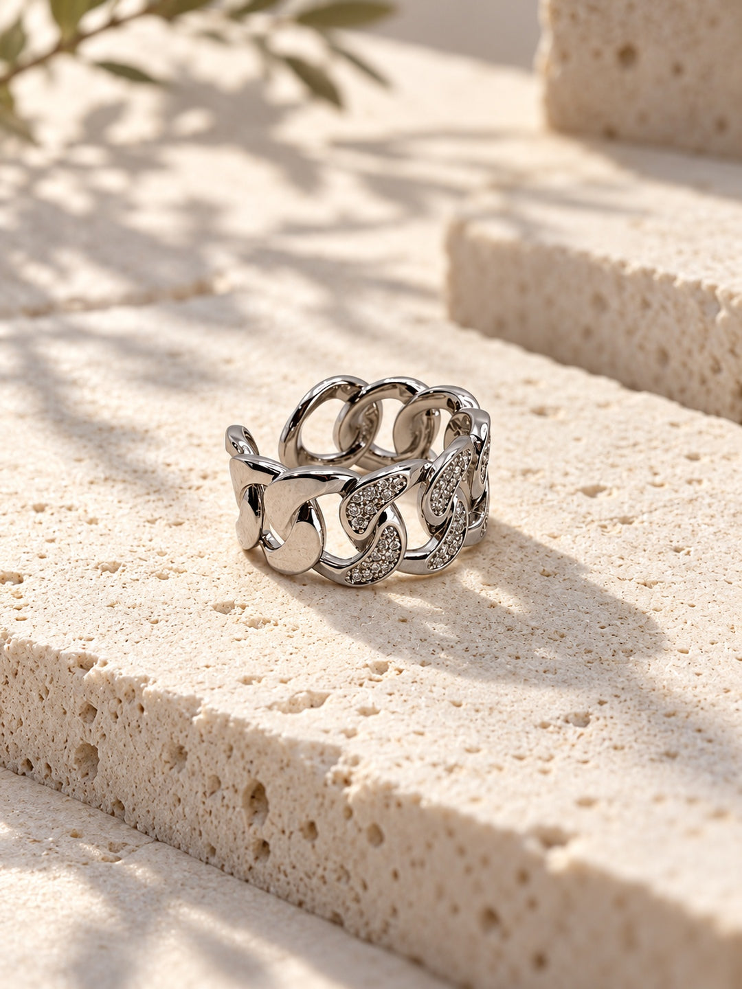 Niska silver-tone stone-studded chain link replica ring on travertine