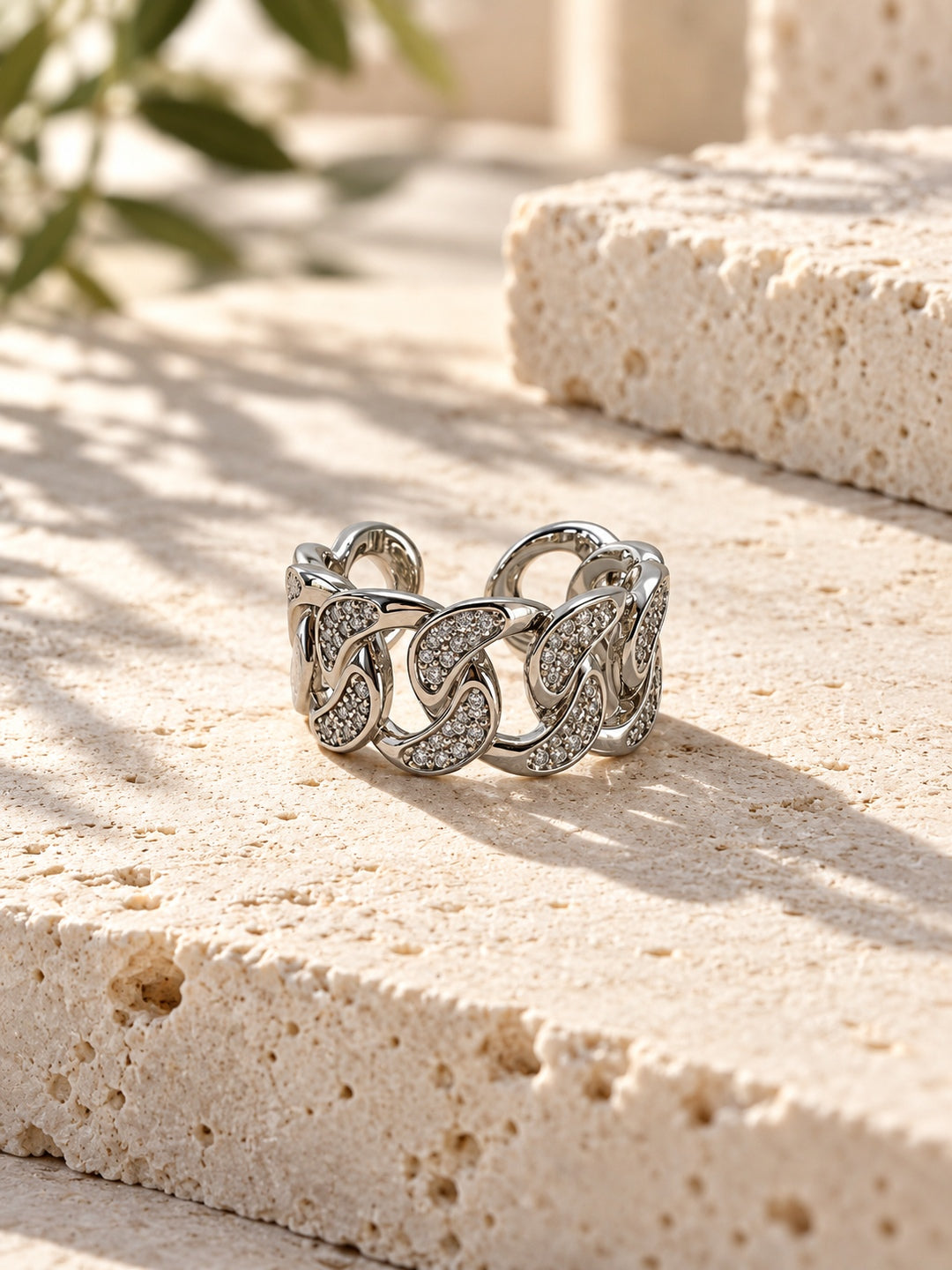 Niska silver-tone stone-studded chain link replica ring on travertine