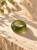 Niska olive green chunky dome replica ring lying flat on travertine
