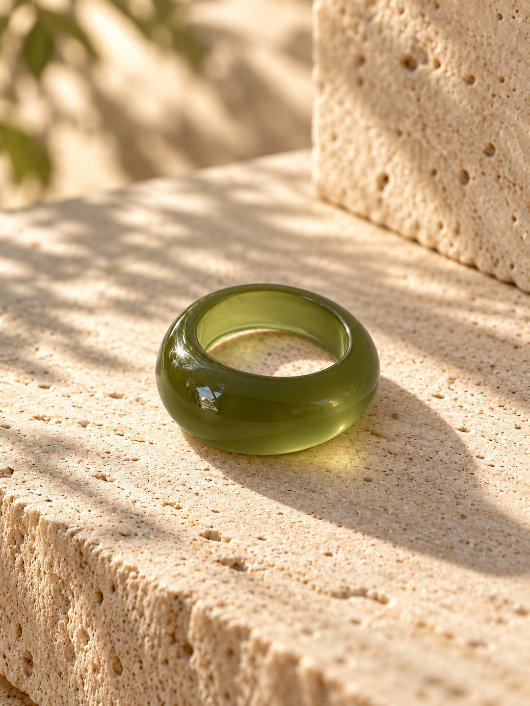 Niska olive green chunky dome replica ring lying flat on travertine